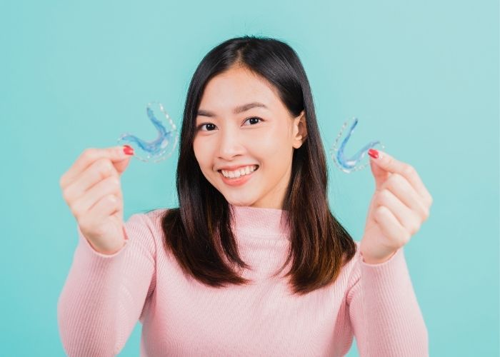 woman holding up 2 pairs of invisalign clear braces (1)