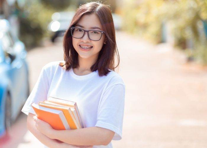 girl with braces holding school books