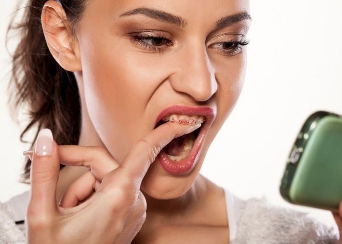 woman looking at stains on teeth in a mirror