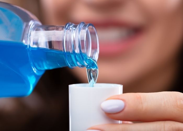 woman pouring blue mouth wash into a cup