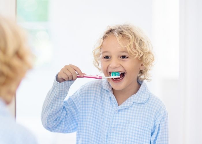 boy smiling and brushing his teeth